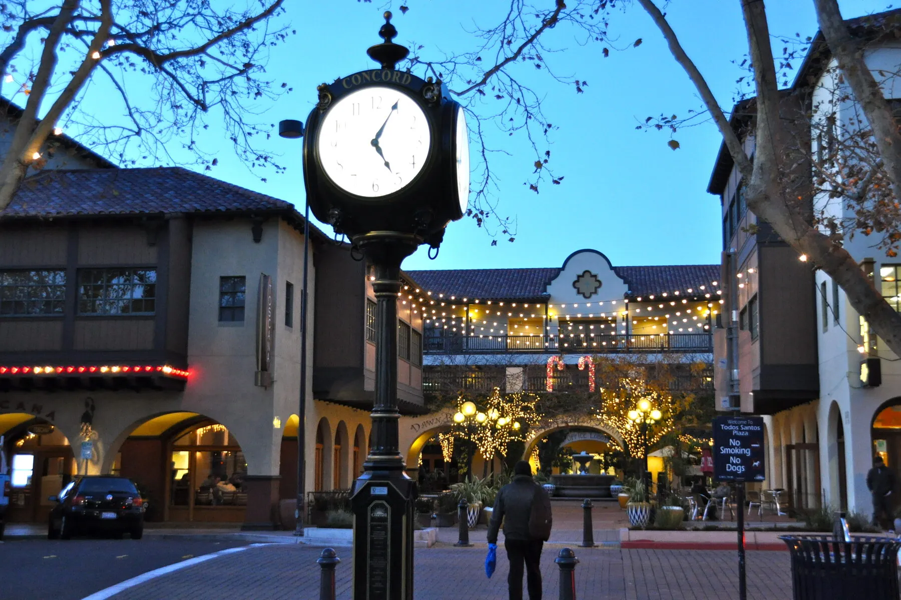 The Concord clock at Todos Santos Plaza at dusk, with string lights over the arcades and storefronts around the square.